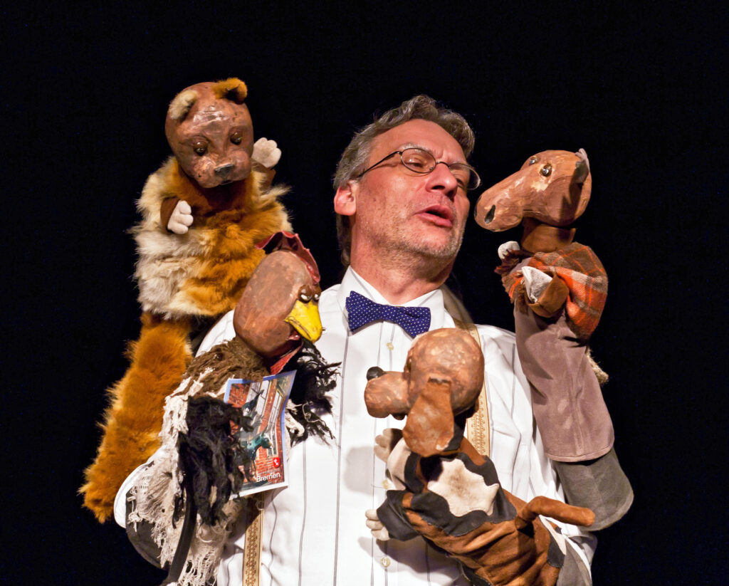 Michal Schmidt mit 4 Figurenpuppen, die die Bremer Stadtmusikanten sind